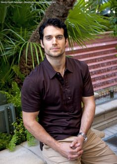 a man sitting on the ground in front of some plants