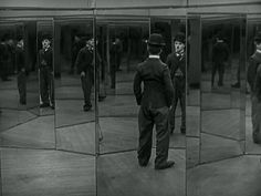 a man standing in front of a mirror wearing a top hat and suit with his hands on his hips