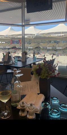 a table with wine glasses and papers on it in front of a large window that overlooks an empty stadium