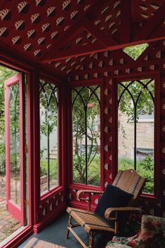 a red room with lots of windows and a wicker chair on the floor in front of it