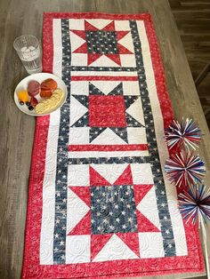 an american flag table runner with red, white and blue stars on it next to a bowl of fruit