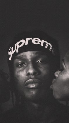 a black and white photo of a man wearing a supreme hat with the word supreme on it