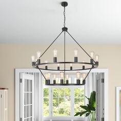 a chandelier hanging over a dining table in a room with white walls and windows