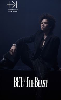 a man sitting on top of a black table next to a dark background with the words bet / the beast