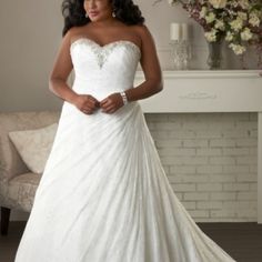 a woman in a white wedding dress standing next to a couch with flowers on it