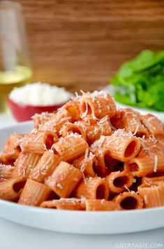 pasta with parmesan cheese and lettuce in a white bowl on a table