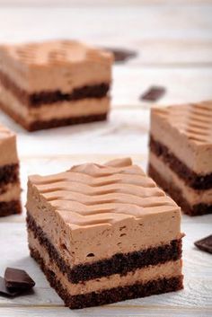 four pieces of chocolate cake sitting on top of a wooden table next to an oreo cookie