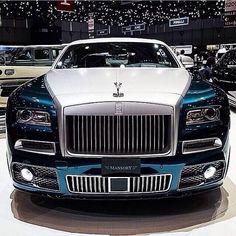 the front end of a blue and white rolls royce on display at an auto show