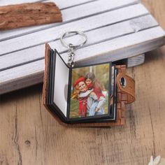 a keychain with an image of two people holding each other on top of a wooden table