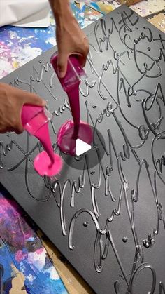 a person is using a pair of pink shoes to decorate a piece of art