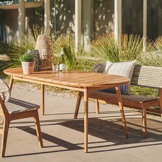 a wooden table with two chairs and a potted plant next to it on a patio