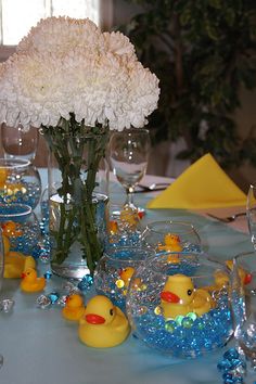 a table set for a baby shower with flowers and rubber ducks