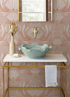 a bathroom with a sink, mirror and wallpaper in pinks and golds