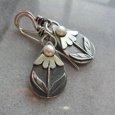 a pair of silver earrings with pearls hanging from them