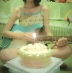 a woman sitting in front of a cake with a guitar