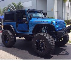 a blue jeep is parked in front of a building with palm trees on the side