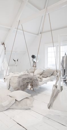a room with white walls and wooden flooring that has swings hanging from the ceiling