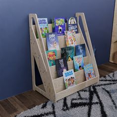 a wooden book stand with books in it on the floor next to a blue wall