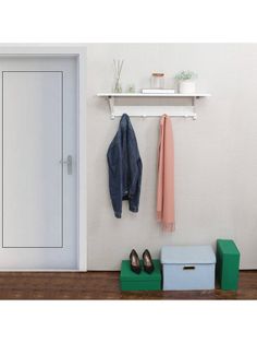 a pair of shoes and coat hangers on a white wall next to a door