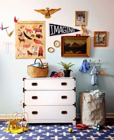 a white dresser sitting next to a blue wall with pictures on the wall above it