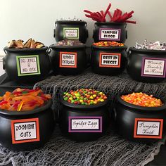 a table topped with black pots filled with candy and candies next to halloween treats