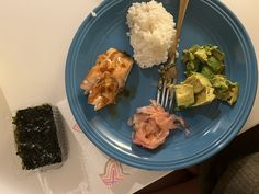 a blue plate topped with sushi and rice next to a piece of broccoli