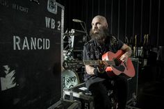 a man with a beard sitting in front of a guitar