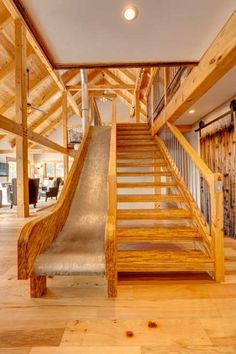 an indoor slide in the middle of a wood floored area with stairs leading up to it