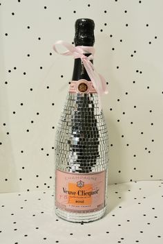 a bottle of champagne with a pink ribbon around it's neck on a polka dot background