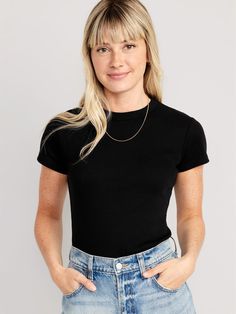 a woman in black shirt and jeans with her hands on her hips looking at the camera