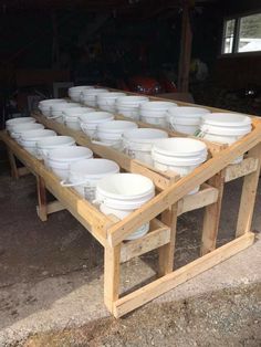 many white bowls are stacked on top of each other in a wooden table with two legs