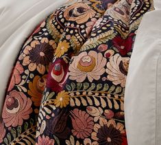 a close up view of the back of a bed with an intricately designed comforter
