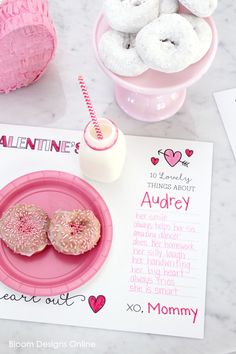 two donuts on a pink plate next to a valentine's day card and other items