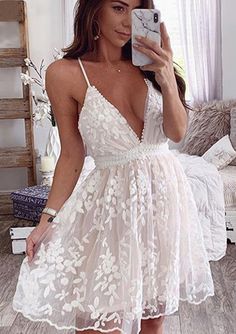 a woman taking a selfie while wearing a white dress and holding a cell phone