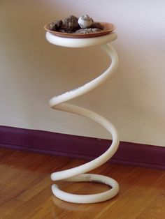 a white sculpture sitting on top of a hard wood floor next to a purple wall