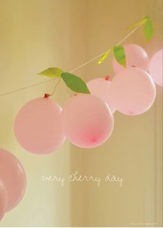 some pink balloons hanging from a string with green leaves on them and the words cherry day written in white