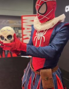 a person in a costume holding a skull and wearing a spider - man mask with one hand