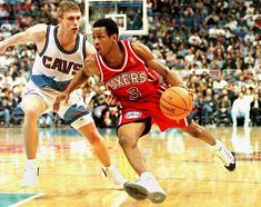 two basketball players in action on the court with fans watching from the stands behind them