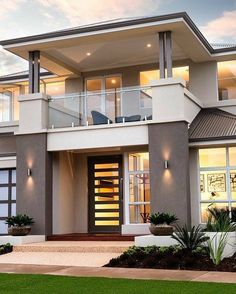 a two story house with large windows and balconies on the second floor is lit up at night