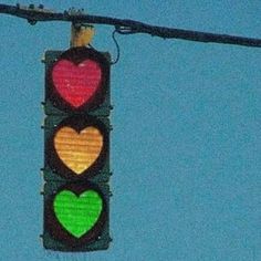 a traffic light with hearts painted on it's red, yellow and green lights