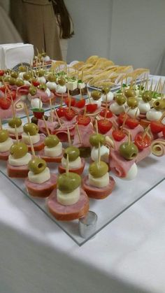 an assortment of appetizers are displayed on a clear platter with toothpicks and olives