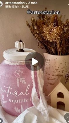 a pink jar sitting on top of a table next to a bird house