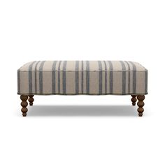 an upholstered bench with wooden legs and striped fabric on the top, against a white background