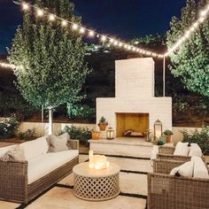 an outdoor living room with wicker furniture and string lights on the ceiling above it