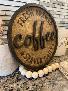 a wooden sign that says fresh brew coffee served daily on a granite countertop next to other items