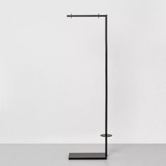 a black metal floor lamp on a white surface with no one in the room behind it