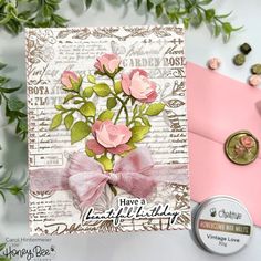 a card with pink roses on it next to some green leaves and a button that says have a beautiful birthday