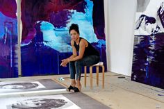 a woman sitting on a chair in front of paintings