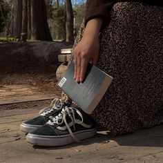 a person sitting on the ground with their foot up and holding an open book in front of them