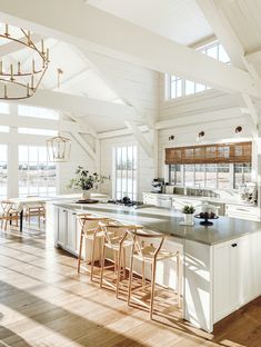 an open kitchen and dining area with white walls, wood floors and vaulted ceilinging